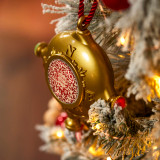 A gold ornament with a QR code hanging on a white frosted lit Christmas tree.